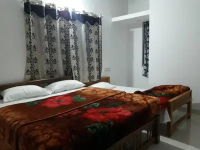 a bedroom with two beds and a window with curtains at Munnar Brindavan Cottage in Munnar