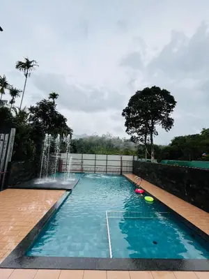 a swimming pool with a water fountain at Royal Plaza Wayanad in Vythiri