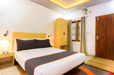 a bedroom with a large bed and a wooden door at Collection O Marhaba Govindapuram in Calicut
