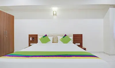 a bedroom with a white bed with a rainbow bedspread at Treebo RJ Residency in Mysore