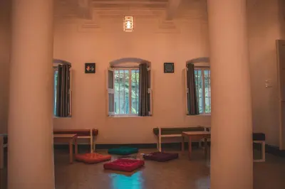 a room with columns and tables and windows at Roambay in Mysore