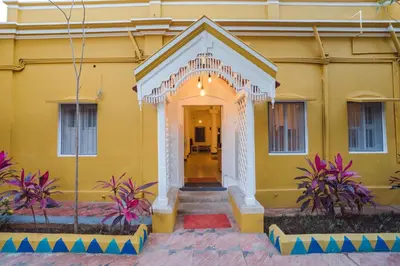 a yellow building with a white entry way at Roambay in Mysore