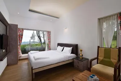 a bedroom with a bed and a window and a chair at Villa Sullivan by VEO - Part of StayVista in Ooty