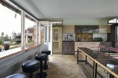 a kitchen with a counter and stools in it at Villa Sullivan by VEO - Part of StayVista in Ooty