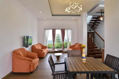 a living room with orange chairs and a table at Villa Sullivan by VEO - Part of StayVista in Ooty