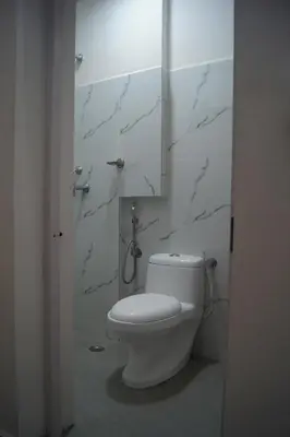 a white bathroom with a toilet and a shower at Cornerbunker in Mysore