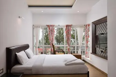 a bedroom with a bed and a large window at Villa Hugel ooty By StayVista in Ooty