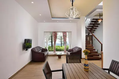 a living room with a wooden table and chairs at Villa Hugel ooty By StayVista in Ooty