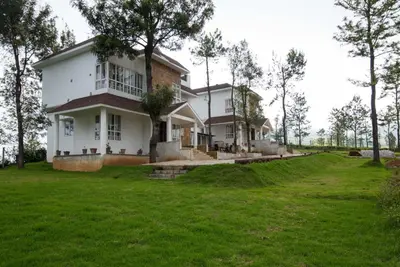 a large white house with a large yard at Villa Hugel ooty By StayVista in Ooty