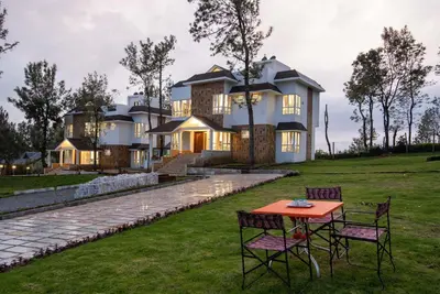 a house with a table and chairs in front of it at Villa Hugel ooty By StayVista in Ooty