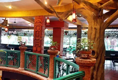 a restaurant with a tree on a balcony at Parklane Hotel in Mysore