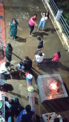 a group of people standing around a fire pit at Ammu's home stay in Panamaram