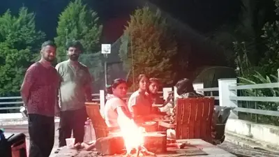 a group of people standing around a fire pit at Ammu's home stay in Panamaram