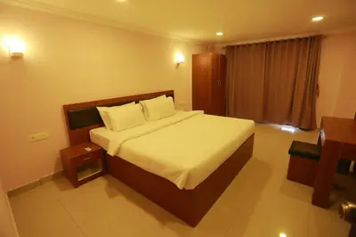 a bedroom with a large bed with white sheets and pillows at Luxora Hotel and Spa in Kozhikode