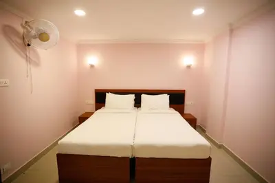 a bedroom with a bed with white sheets and a fan at Luxora Hotel and Spa in Kozhikode