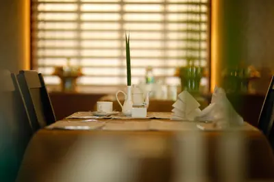 a wooden table with a table cloth and cups on it at Luxora Hotel and Spa in Kozhikode