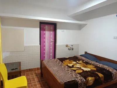 a bedroom with a bed and a yellow chair at Osprey individual Cottage in Ooty