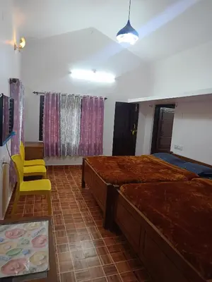 a bedroom with two beds and a yellow chair at Osprey individual Cottage in Ooty
