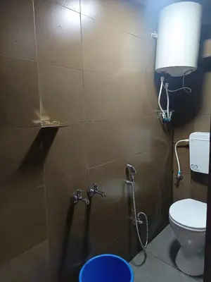 a bathroom with a toilet and a lamp on the wall at Osprey individual Cottage in Ooty