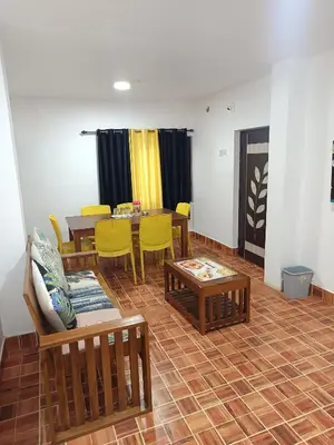 a living room with a table and yellow chairs at Osprey individual Cottage in Ooty