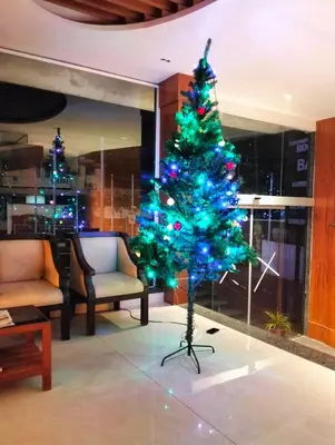 a green christmas tree in a room with chairs at GAYATHRI HOTELS in Badagara