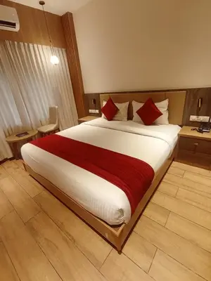 a large bed with red pillows in a hotel room at GAYATHRI HOTELS in Badagara