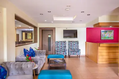 a living room with two couches and a tv at Vinayaga Inn by Poppys, Ooty in Ooty
