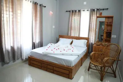 a bed in a room with a chair and a bed sidx sidx sidx at kailasa stays in Chekadi