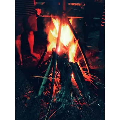 a person is sitting around a fire at kailasa stays in Chekadi