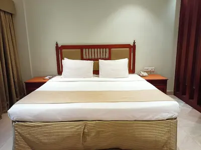 a bedroom with a large bed with white sheets and pillows at Hotel CLOUD 9 in Kotamangalam