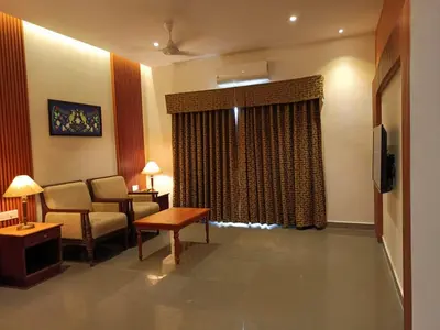 a living room with a couch and a chair and a television at Hotel CLOUD 9 in Kotamangalam