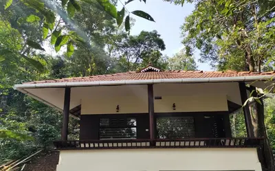 a building with a roof with trees in the background at Green Garden Lotus in Vythiri