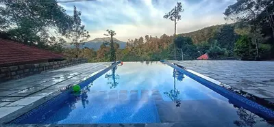 a swimming pool with blue water and mountains in the background at Green Garden Lotus in Vythiri