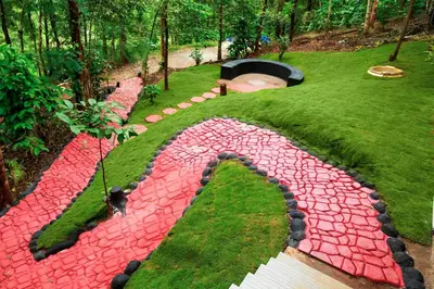 a garden with red rocks in the grass at Green Garden Lotus in Vythiri