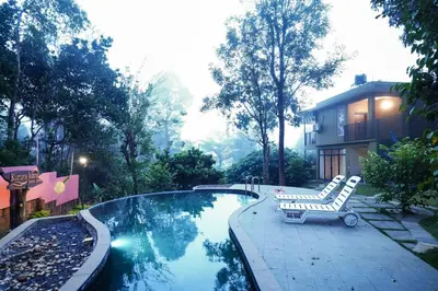 a swimming pool with a bench and a chair next to a house at Kuruva Island Resort And Spa - By KABINI BREEZE in Mananthavady