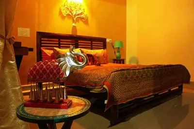 a bedroom with a bed and a table with a lamp at Siddhi Aloha in Madikeri