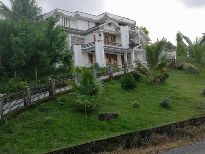 a house on a grassy hill with a fence at Viewpointwayanad in Mananthavady