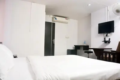 a bedroom with a white bed and a desk at MALAPPURAM RESIDENCY in Malappuram
