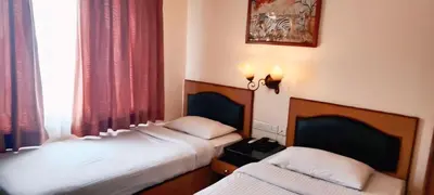 two twin beds in a room with a window at Hotel Nahar Manchester Inn in Coimbatore