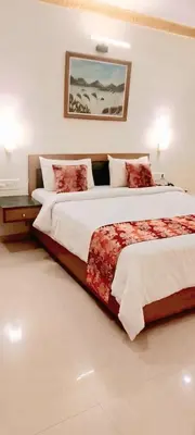 a bedroom with two beds and a painting on the wall at Hotel Nahar Manchester Inn in Coimbatore