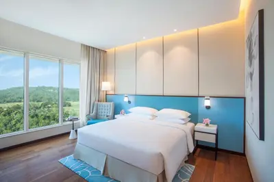 a bedroom with a large bed with blue walls and windows at Hyatt Regency Thrissur in Trichūr