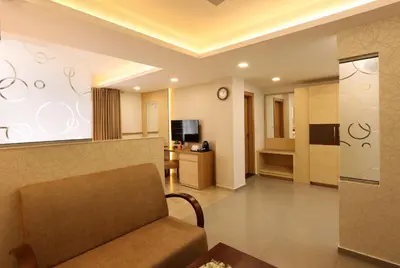 a living room with a couch and a kitchen at Flora Charishma Residency Aluva in Cochin