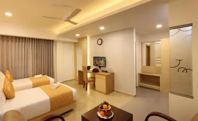 a hotel room with two beds and a table at Flora Charishma Residency Aluva in Cochin