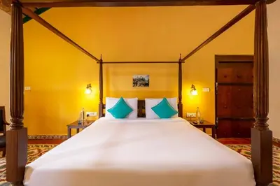 a bedroom with a large bed with blue pillows at amã Stays & Trails, Rare Earth Estate in Madikeri
