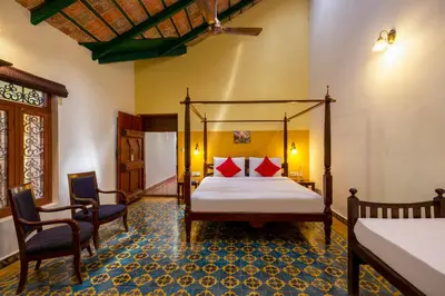 a bedroom with a canopy bed and two chairs at amã Stays & Trails, Rare Earth Estate in Madikeri