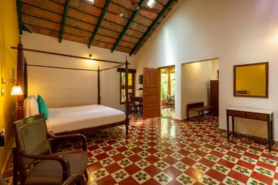 a bedroom with a bed and a table and chairs at amã Stays & Trails, Rare Earth Estate in Madikeri