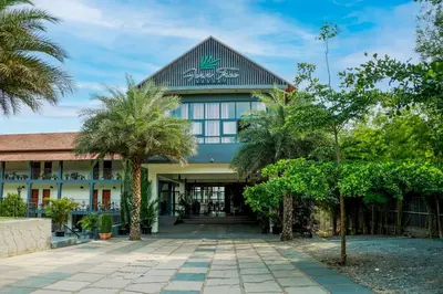 a building with palm trees in front of it at Fern Tree Resort in Mananthavady