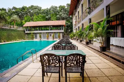a table with chairs next to a swimming pool at Fern Tree Resort in Mananthavady