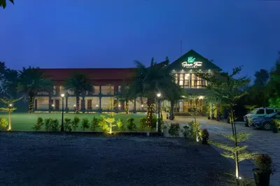 a building with palm trees in front of it at night at Fern Tree Resort in Mananthavady