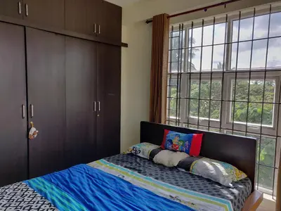 a bedroom with a bed and a large window at Swag Apartment in Mysore